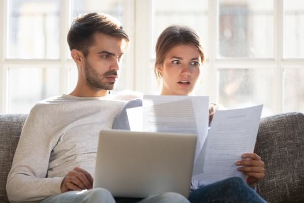 Couple looking at paperwork with shocked look on their faces
